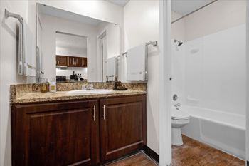 A bathroom with a white tub and wooden cabinets.